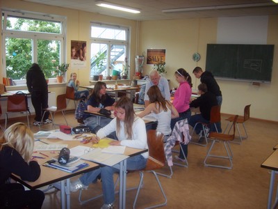 Schülerinnen und Schüler arbeiten an Tischen im Klassenzimmer.